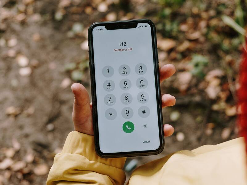 Eine Person hält ein Smartphone mit einem aktivierten Notrufbildschirm, auf dem die Nummer 112 angezeigt wird.