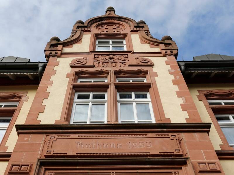 Das Bild zeigt die Fassade eines historischen Gebäudes mit aufwendigen Verzierungen und der Jahreszahl 1903 über einem der Fenster.