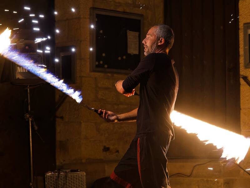 Ein Mann führt in der Nacht eine Feuershow mit einem brennenden Schwert auf.