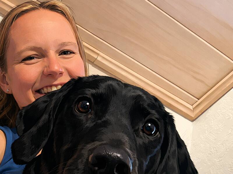 Eine lächelnde Frau posiert für ein Foto mit einem schwarzen Hund im Vordergrund.