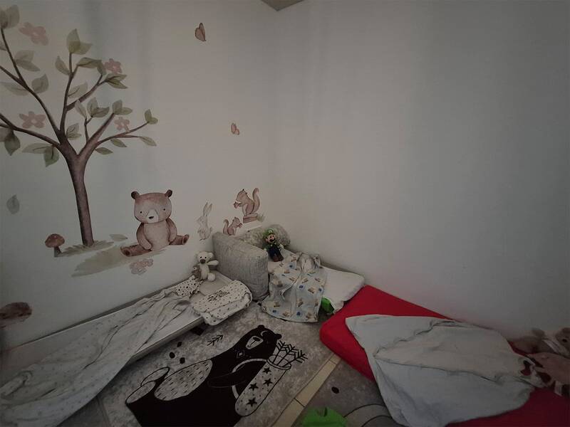 Ein Kinderzimmer mit Matratzen auf dem Boden und einer Wandbemalung, die einen Baum, ein Bär und andere Waldtiere darstellt.