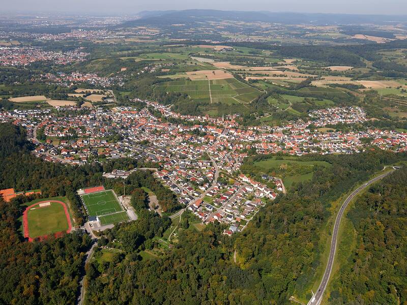 Das Bild zeigt eine Luftaufnahme einer ländlichen Gegend mit Dörfern, Feldern, Wäldern und einem Sportplatz in der unteren linken Ecke.